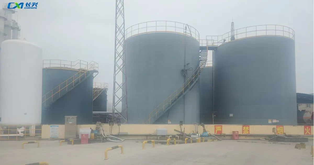 Large blue storage tanks with safety signage at Shandong Changxing Plastic Additives DOTP production facility
