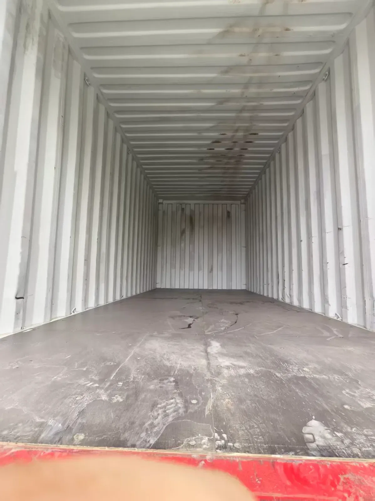 Factory worker cleaning and sweeping the container interior before DOTP flexibag installation