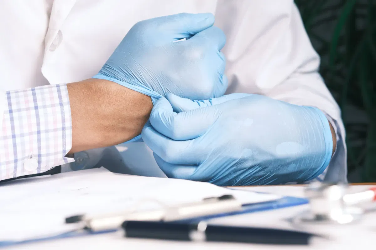 Clinician putting on a disposable examination glove before a patient examination