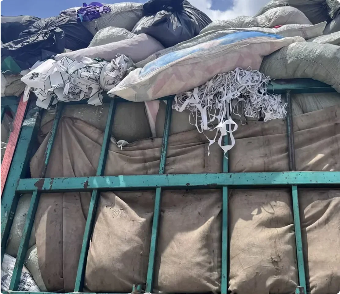 Truck loaded with bagged waste polyester fabric scraps arriving for DOTP chemical recycling