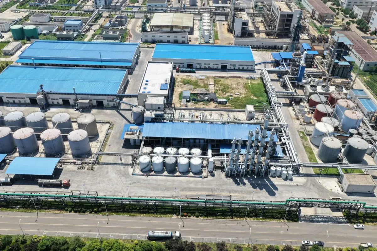 Aerial overview of Wansheng DOTP factory showing raw-material yard, distillation towers, tank farm and biomass gasifier