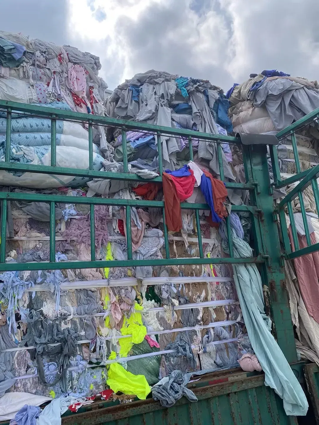 Compressed bales of waste polyester textiles and used clothing loaded for polyester recycling into DOTP